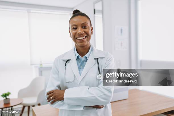 portrait of a smiling female doctor looking at camera - dokterspraktijk stockfoto's en -beelden