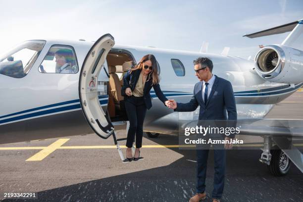 mujer de negocios bajando de un jet privado con un colega - aviacion fotografías e imágenes de stock