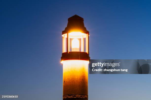lighthouse illuminated against the sky at dusk, dalian, china. - beacon stock pictures, royalty-free photos & images
