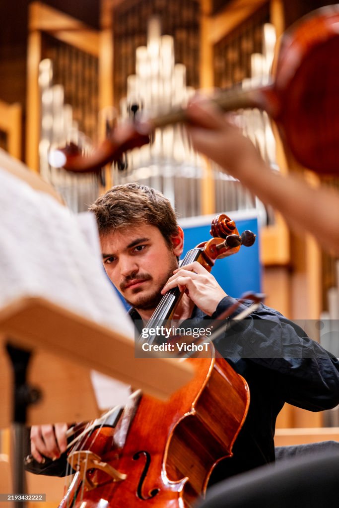 Focused Cellist Playing During Orchestra Rehearsal