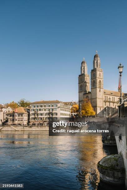 view of the grossmünster cathedral and the river in zurich on a sunny day - zurich stock pictures, royalty-free photos & images