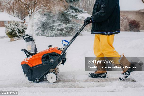 person operating a snowblower on a snow covered sidewalk - snow blower stock pictures, royalty-free photos & images