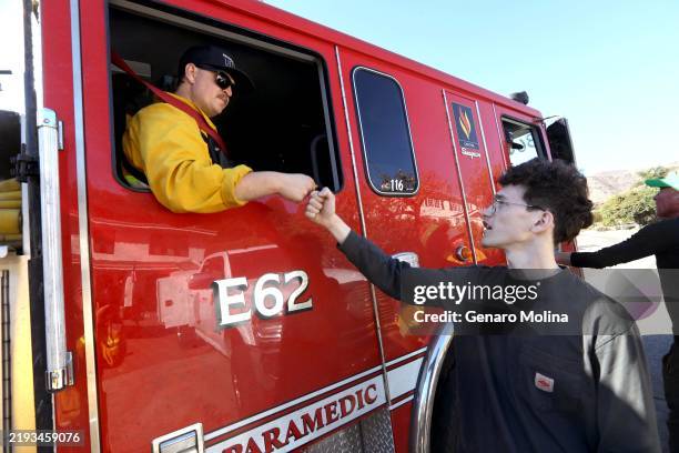 Colton Foster gives Redondo Beach firefighter Declan O'Brien a fist bump of thanks in the Pacific View Estates neighborhood, near the Getty Villa, in...