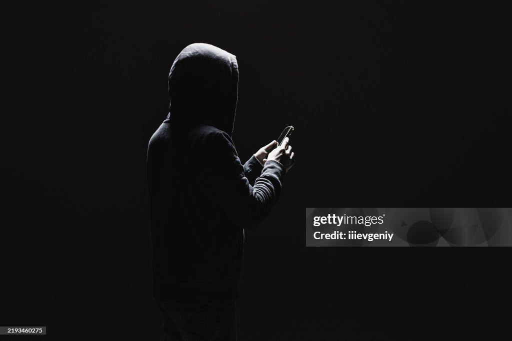 Silhouette des Mannes in der Kapuze mit Telefon