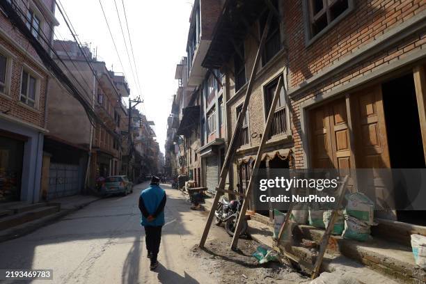 Man walks past a damaged home supported by wooden beams crippled by the 2015 ''Nepal Earthquake'' in Lalitpur, Nepal, on January 15, 2025. A decade...