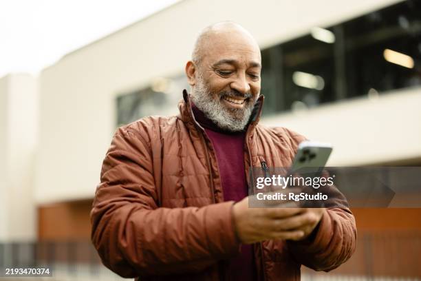 mature latin man using smartphone on the move - old man texting stock pictures, royalty-free photos & images