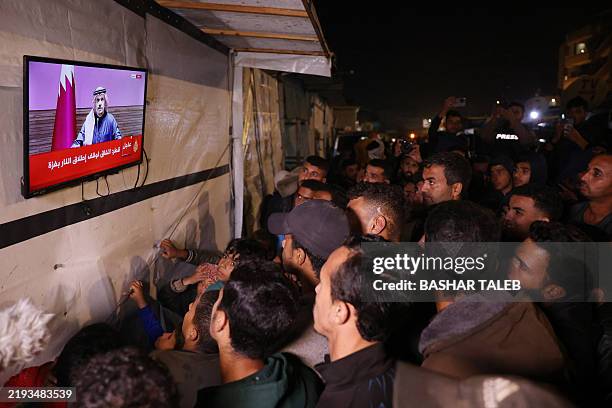 People watch the live television broadcast of a press conference being addressed by Qatar's Prime Minister Sheikh Mohammed bin Abdulrahman bin Jassim...
