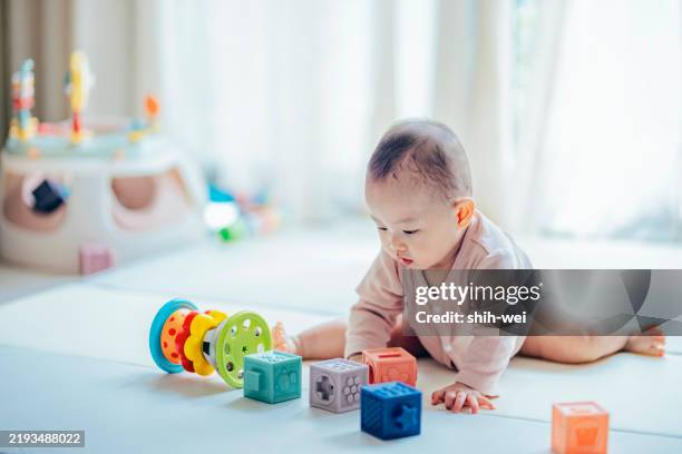 creative little toddler girl playing with colourful building blocks at home - baby girls stock pictures, royalty-free photos & images
