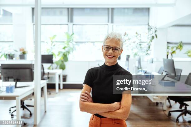 creative senior entrepreneur working in creative office with pottery and interior design solutions. gray hair woman standing with arms crossed and smiling at camera - creative director stock pictures, royalty-free photos & images