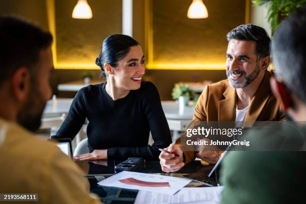cheerful iranian businesswoman smiling towards male colleague in business meeting - encouragement stock pictures, royalty-free photos & images