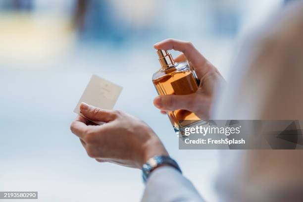 hand spraying perfume on card to test fragrance in closeup view - perfumado imagens e fotografias de stock