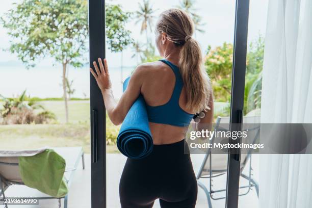 woman holding yoga mat looking at scenic view - retreating stock pictures, royalty-free photos & images