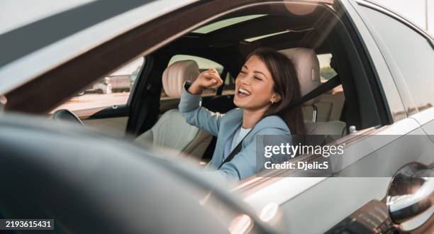 donna che si gode la musica mentre guida la sua nuova auto - autista mestiere foto e immagini stock