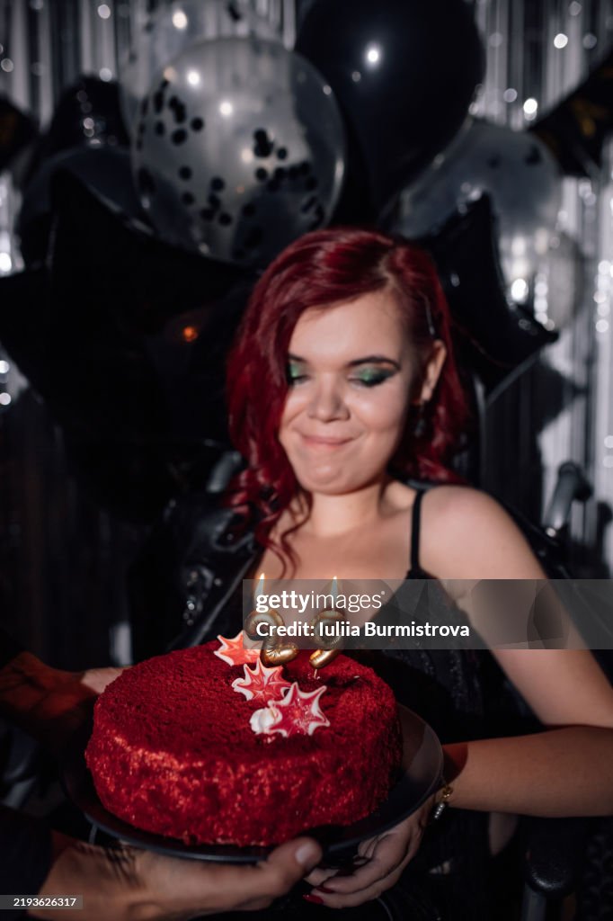 Young woman in wheelchair celebrates birthday with a beautifully decorated cake and joyful atmosphere at a party