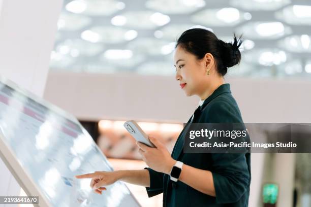 imprenditrice asiatica che usa lo smartphone e tocca lo schermo di un dispositivo self-service in un negozio. navigatore archivio dispositivi. autoacquisto. - interattività foto e immagini stock