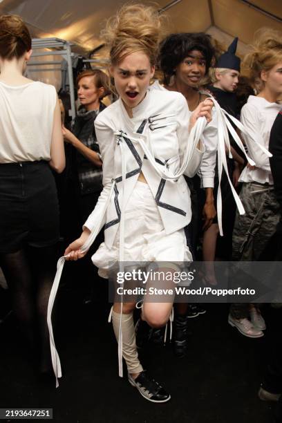 Backstage at the Marithe + Francois Girbaud show during Paris Fashion Week Spring/Summer 2010, a model wears white knickerbockers and a bondage...