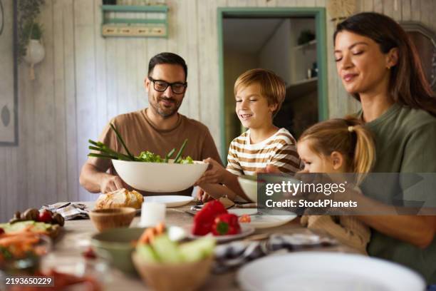 happy family having a meal in dining room. - sentarse a comer fotografías e imágenes de stock