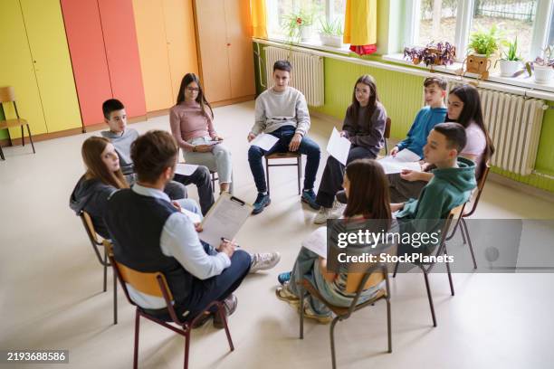 eine gruppe von jugendlichen sitzt mit einer lehrerin im kreis - ausbilder stock-fotos und bilder