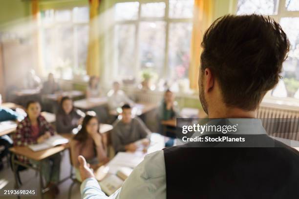 ein lehrer unterrichtet eine gruppe von jugendlichen in einem klassenzimmer - ausbilder stock-fotos und bilder