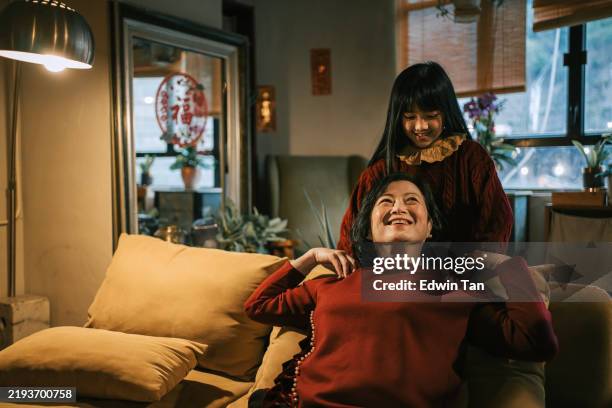 chinesische enkelin massiert großmutter während des chinesischen neujahrsessens familientreffen - kinder massage stock-fotos und bilder