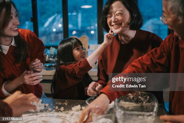 joven china juguetona que toca la cara del padre con harina pegajosa mientras prepara el postre de bola de arroz glutinoso tangyuan durante el festival del año nuevo chino del solsticio de invierno - solsticio de invierno fotografías e imágenes de stock