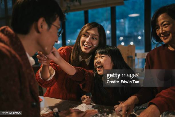 playful chinese young girl touching father face with sticky flour while preparing tangyuan glutinous rice ball dessert during winter solstice chinese new year festival - tangyuan stock pictures, royalty-free photos & images