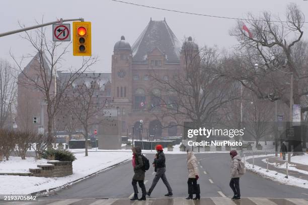 People cross an intersection at College Street and Queen's Park as Toronto receives fresh snowfall in Ontario, Canada, on January 16, 2025. The...