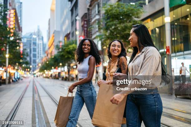 trois jeunes amies marchant en portant des sacs de courses dans la rue à sydney en australie - accro du shopping photos et images de collection