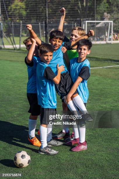 niños celebrando una victoria de fútbol juntos en un campo - juego en equipo fotografías e imágenes de stock