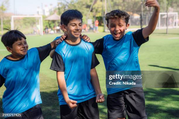 excited group of kids celebrating on a soccer field - sports strip stock pictures, royalty-free photos & images