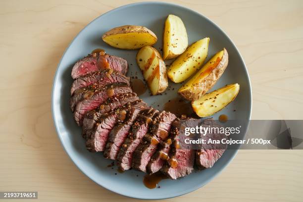 a plate with a sliced beef steak and roasted potato wedges - fillet steak stock pictures, royalty-free photos & images