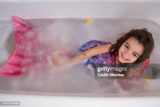 smiling girl wearing mermaid costume playing in bathtub - real mermaid images stock pictures, royalty-free photos & images
