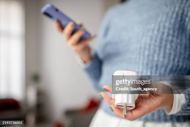 person using smartphone with smart plug device - electrical plug stock pictures, royalty-free photos & images
