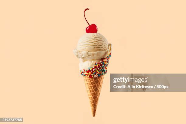 a photo of an ice cream cone with a single scoop of vanilla ice cream with a cherry on top - barquilla de helado fotografías e imágenes de stock
