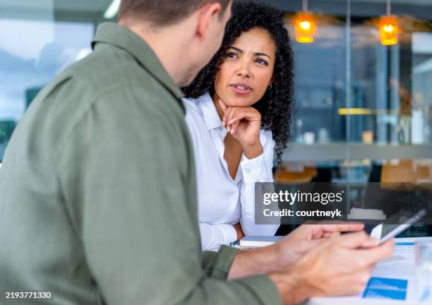 worried business man and business woman in a meeting at the office. the man is holding a digital tablet. the woman looks upset. - suspicion stock pictures, royalty-free photos & images