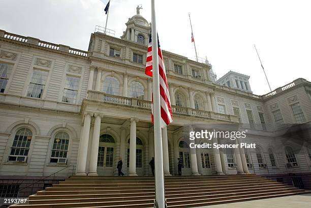 Flag flies at half mast as New York City police officers guard the entrance to City Hall one day after two people were killed in a shooting inside...