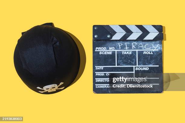 pirate hat and movie clapperboard with the word 'piracy' written on it, on yellow background. pirate, thief, steal, copyright, streaming and legal. - digital camcorder stock pictures, royalty-free photos & images