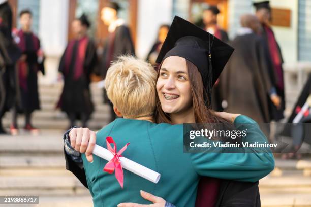 a proud mother embraces her graduate daughter - diploma stock pictures, royalty-free photos & images