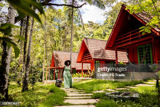 mid adult tourist woman walking with luggage and arriving on inn - ecoturismo imagens e fotografias de stock