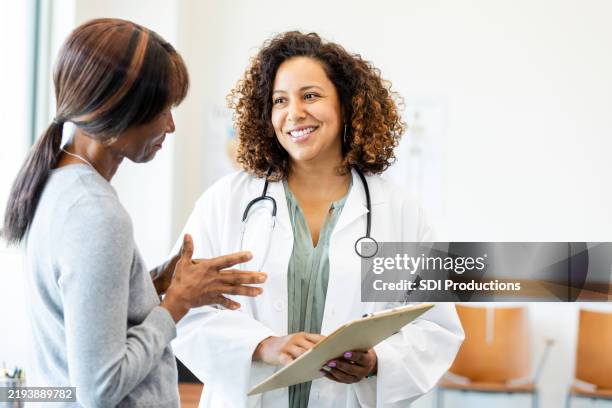 arzt und patient diskutieren über gesundheitsversorgung in der klinik - arzt stock-fotos und bilder