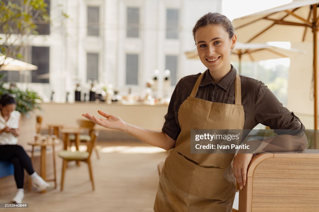 Smiling Cafe Worker Welcoming Customers in an Outdoor Coffee Shop Setting