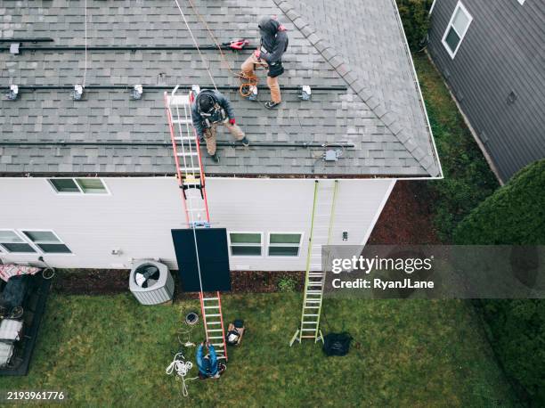 aerial view of solar energy technicians working to install solar panels on residential roof - telhado imagens e fotografias de stock