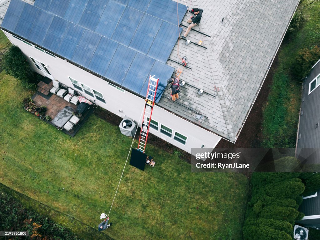 Aerial View of Solar Energy Technicians Working To Install Solar Panels on Residential Roof