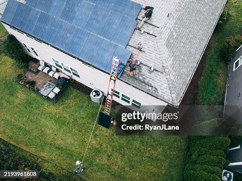 Aerial View of Solar Energy Technicians Working To Install Solar Panels on Residential Roof Aerial View of Solar Energy Technicians Working To Install Solar Panels on Residential Roof
