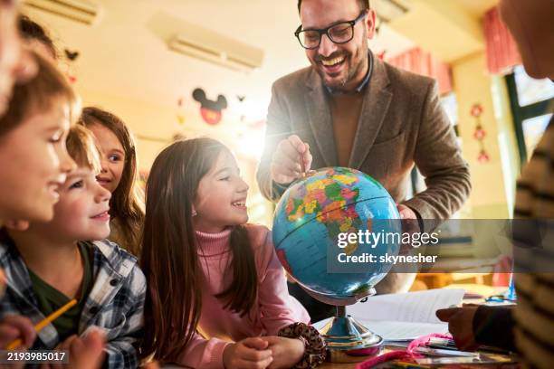 happy teacher and his students analyzing globe in the classroom. - physical geography stock pictures, royalty-free photos & images