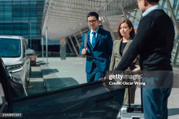 driver assisting business people into cab - taxifahrer stock-fotos und bilder