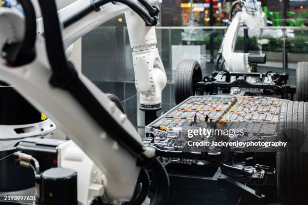 electric car battery installation using a robotic arm for futuristic vehicle assembly - elektromotor stock-fotos und bilder