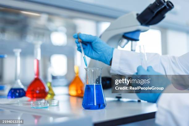 científico que añade fluido con pipeta en un matraz erlenmeyer en laboratorio - matraz fotografías e imágenes de stock