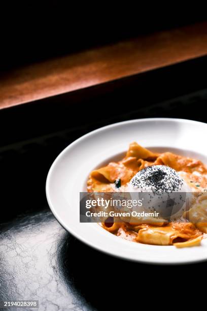 italian pasta dish with pappardelle in rich tomato sauce, topped with creamy burrata and black pepper, gourmet presentation, fine dining experience, classic italian cuisine - foodstyling stockfoto's en -beelden