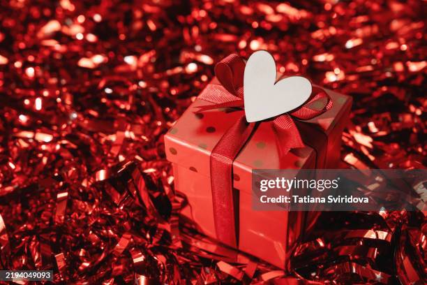 red gift box with bow ribbon on red gradient background with white heart - valentines table stock pictures, royalty-free photos & images